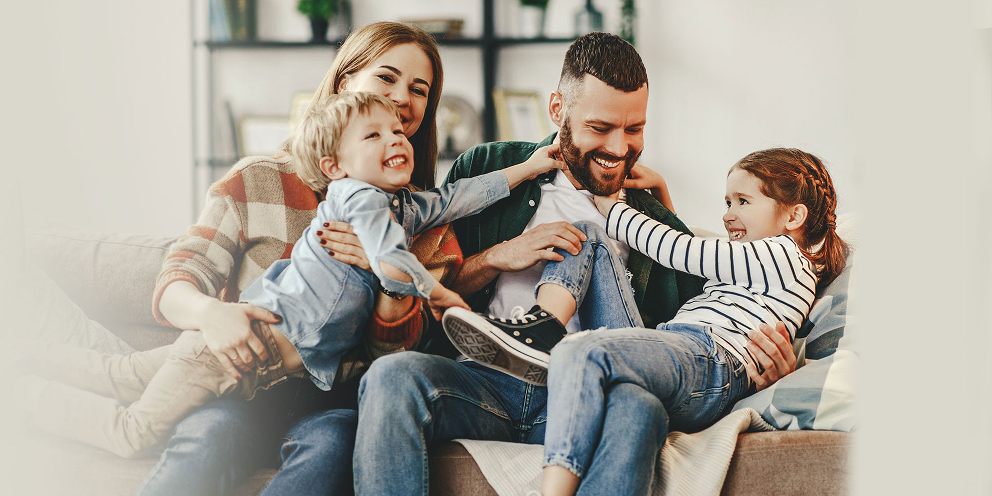 family wrestling on the couch and smiling