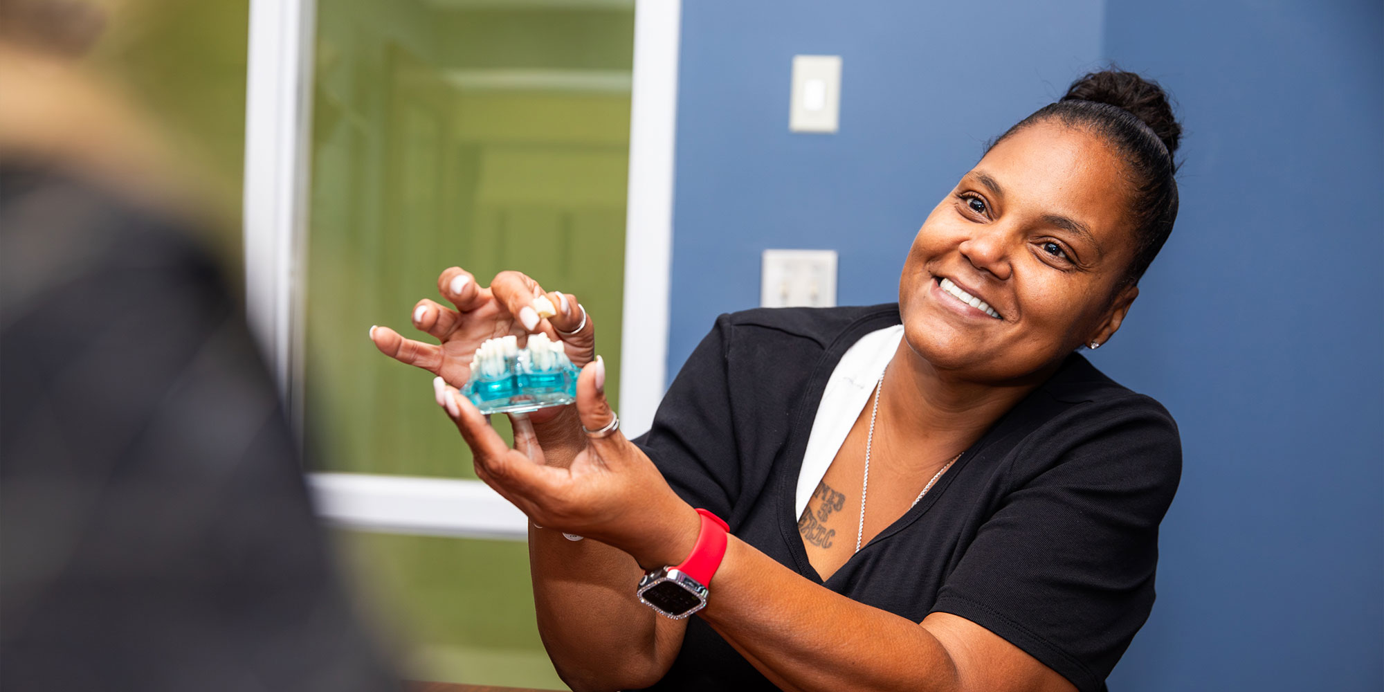 patient smiling and looking at bridge model within the dental practice